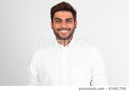 Happy young bearded Indian man smiling against white background Happy young bearded Indian man smiling against white background 63461790