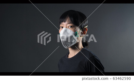 Asian woman wearing n95 healthy mask for protect coronavirus or covid-19 and pm 2.5 dangerous dust from bad air pollution which shoot in studio with clear black color background. 63462590