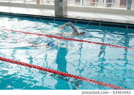 Racing against each other in swimming pool 63463942