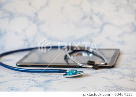 Stethoscope and notebook Tablet in the fingers of hand 63464135