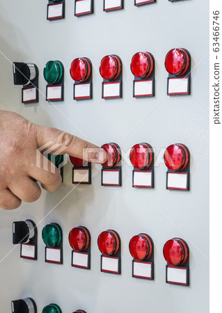 hand presses a button on the Control panel with many roundbuttons of industrial equipment 63466746