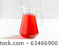 Glass jar of red berry drink on wooden table 63466900