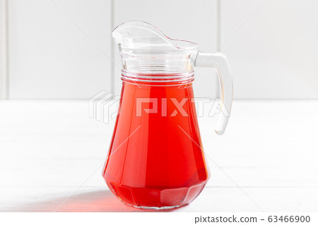 Glass jar of red berry drink on wooden table Glass jar of red berry drink on wooden table 63466900