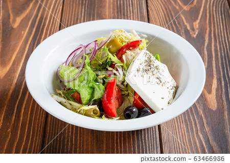 Plate of fresh greek salad on wooden table Plate of fresh greek salad on wooden table 63466986