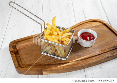 Basket of french fries with ketchup on wooden desk Basket of french fries with ketchup on wooden desk 63466987