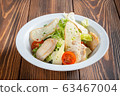Plate of caesar salad with chicken on wooden table 63467004