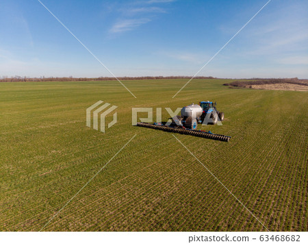 Tractor applying liquid mineral fertilizers to the soil on winter wheat 63468682