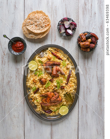 Chicken Mandi with dates on a wooden table.  63469398