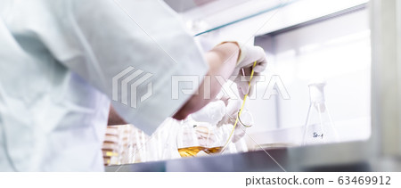 Female scientist working with laminar flow at corona virus vaccine development laboratory research facility. Female scientist working with laminar flow at corona virus vaccine development laboratory research facility. 63469912