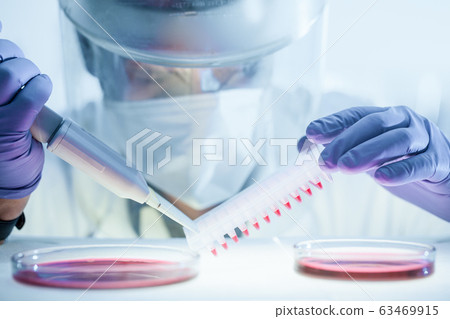 Scientist working in the corona virus vaccine development laboratory research with a highest degree of protection gear. Scientist working in the corona virus vaccine development laboratory research with a highest degree of protection gear. 63469915