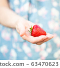 A woman holding a strawberry in her hand 63470623