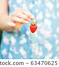 A woman holding a strawberry in her hand 63470625