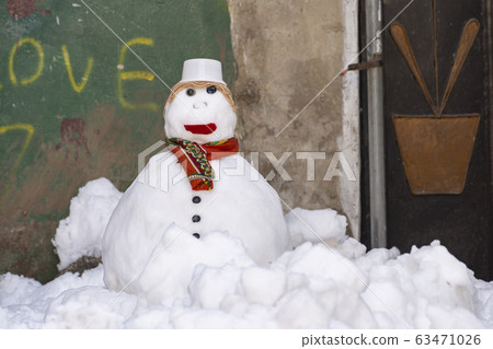 Snowman with scarf and hat stand alone at alley 63471026