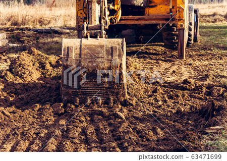The bucket excavator picks up the soil to pave the The bucket excavator picks up the soil to pave the 63471699