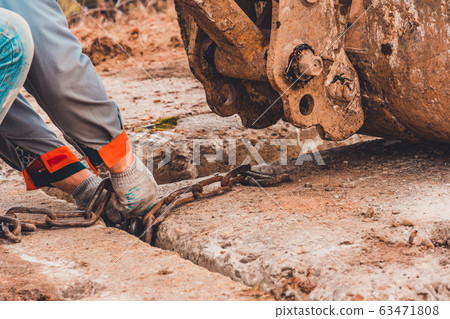 The worker clings the chain to the excavator The worker clings the chain to the excavator 63471808