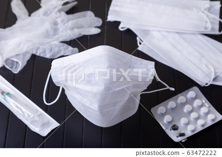 Medical white masks on a black background. Surgical protective mask against viruses and bacteria. The concept of protection against influenza, coronavirus, tonsillitis. Medical white masks on a black background. Surgical protective mask against viruses and bacteria. The concept of protection against influenza, coronavirus, tonsillitis. 63472222