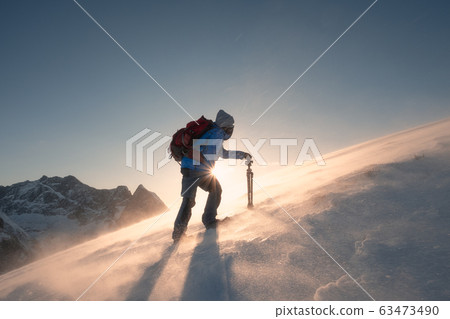 Man with tripod are climbing on slope hill on 63473490