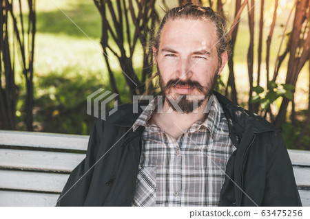 Young bearded Asian man sitting in a park 63475256