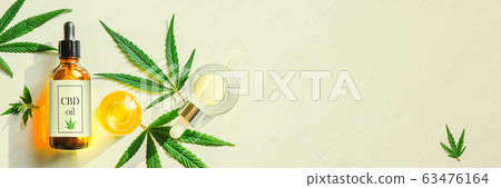 Glass brown bottle with cannabis CBD oil with label and hemp leaves on a marble background. Copy space 63476164