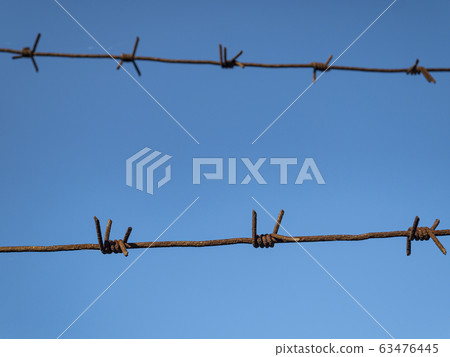 Barbed wire against the blue sky. 63476445
