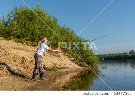 Photo of a young boy fishing outdoors on a summer day. 63477593