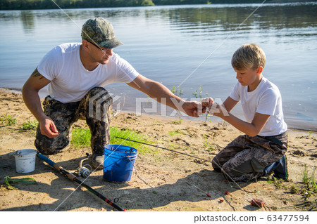 Teamwork. Father and son fishing on a summer weekend. Hobby and sport activity, preparing fish bait. Teamwork. Father and son fishing on a summer weekend. Hobby and sport activity, preparing fish bait. 63477594