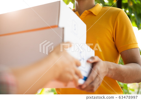 Happy delivery man in yellow polo shirt uniform 63478997