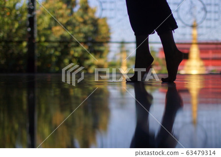 Silhouette of woman's feet walking on tiptoe on floor of Buddhist temple, mirror reflection of feet in floor, closeup Silhouette of woman's feet walking on tiptoe on floor of Buddhist temple, mirror reflection of feet in floor, closeup 63479314
