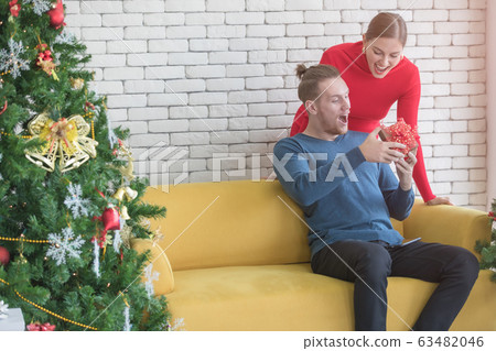 Caucasian couple. Woman giving gift to boyfriend.. Caucasian couple. Woman giving gift to boyfriend.. 63482046