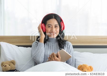 Asian woman sits and wearing headphone in Asian woman sits and wearing headphone in 63483610
