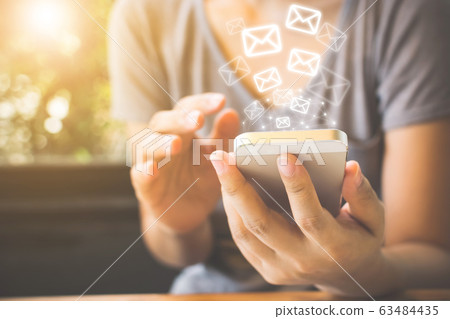 Close-up image of female hands using smartphone with icon envelope email 63484435