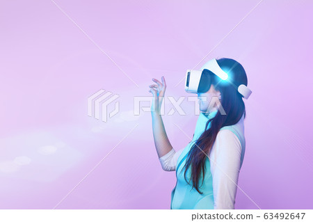 Woman is using virtual reality headset. 63492647