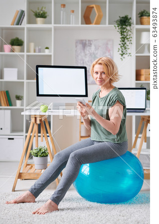 Pretty mature female with smartphone searching for online fitness course 63493874