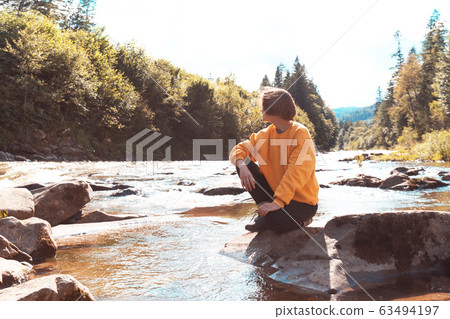 tourist girl sitting on the bank of a mountain tourist girl sitting on the bank of a mountain 63494197