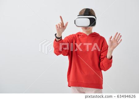 Contemporary teenage girl in hoodie and vr headset pointing at virtual display Contemporary teenage girl in hoodie and vr headset pointing at virtual display 63494626