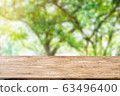 light brown wood table on blurred public garden background with sunlight 63496400