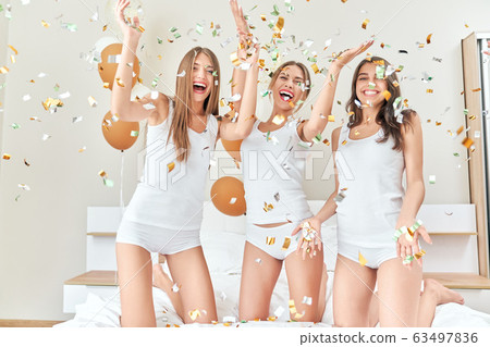 Girls having party with confetti in bedroom. 63497836