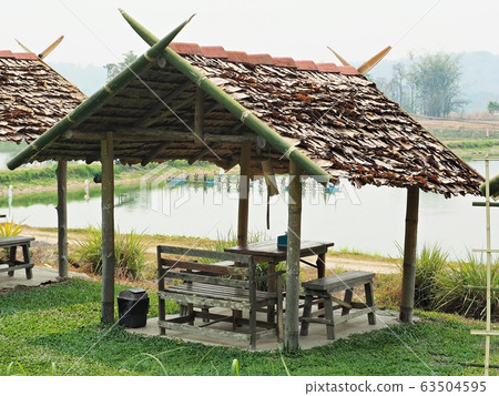Wooden gazebo wrapped with natural dried leaves on the roof. Wooden gazebo wrapped with natural dried leaves on the roof. 63504595