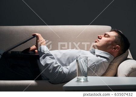 businessman is lying on the sofa with laptop and businessman is lying on the sofa with laptop and 63507432