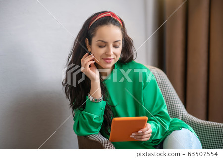 Young woman in green blouse looking attentively at sheet. 63507554