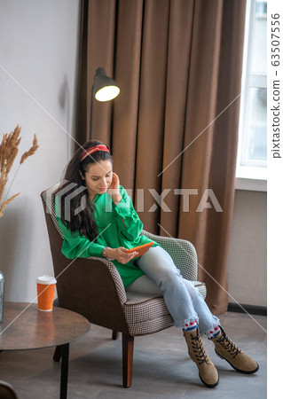 Young woman sitting in a chair looking at a tablet computer. 63507556