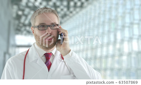 Doctor wearing glasses talks to patient on his smartphone. Shot on Red camera Doctor wearing glasses talks to patient on his smartphone. Shot on Red camera 63507869