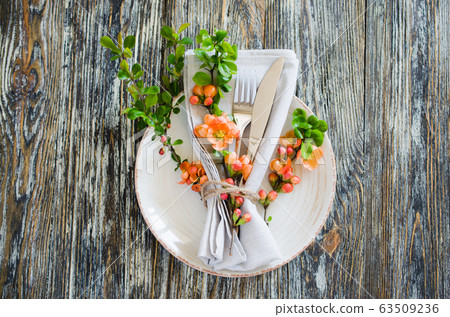 Vintage table setting with delicate flowers on a linen napkin on on rustic shabby table, close-up. 63509236
