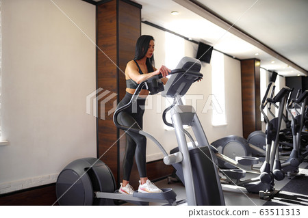 Training in the gym Fitness girl coach working on Step machine and showing her figure posing in a sports suit 63511313