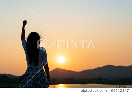 Soft focus of woman with fist in the air during sunset Soft focus of woman with fist in the air during sunset 63512347