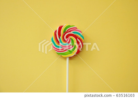 Top view a lollipop  on yellow background. Rainbow lollipop with paper Frame. Photo Creative and copy concept Space idea. 63516103