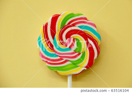 Top view a lollipop  on yellow background. Rainbow lollipop with paper Frame. Photo Creative and copy concept Space idea. 63516104