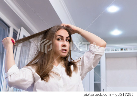 Girl in white shirt combs her hair Girl in white shirt combs her hair 63517295
