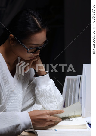 Girl in white shirt reading many textbooks on 63518710