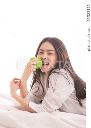 Beautiful asian woman wearing white shirt with holding green apple isolated on white background Beautiful asian woman wearing white shirt with holding green apple isolated on white background 63522113
